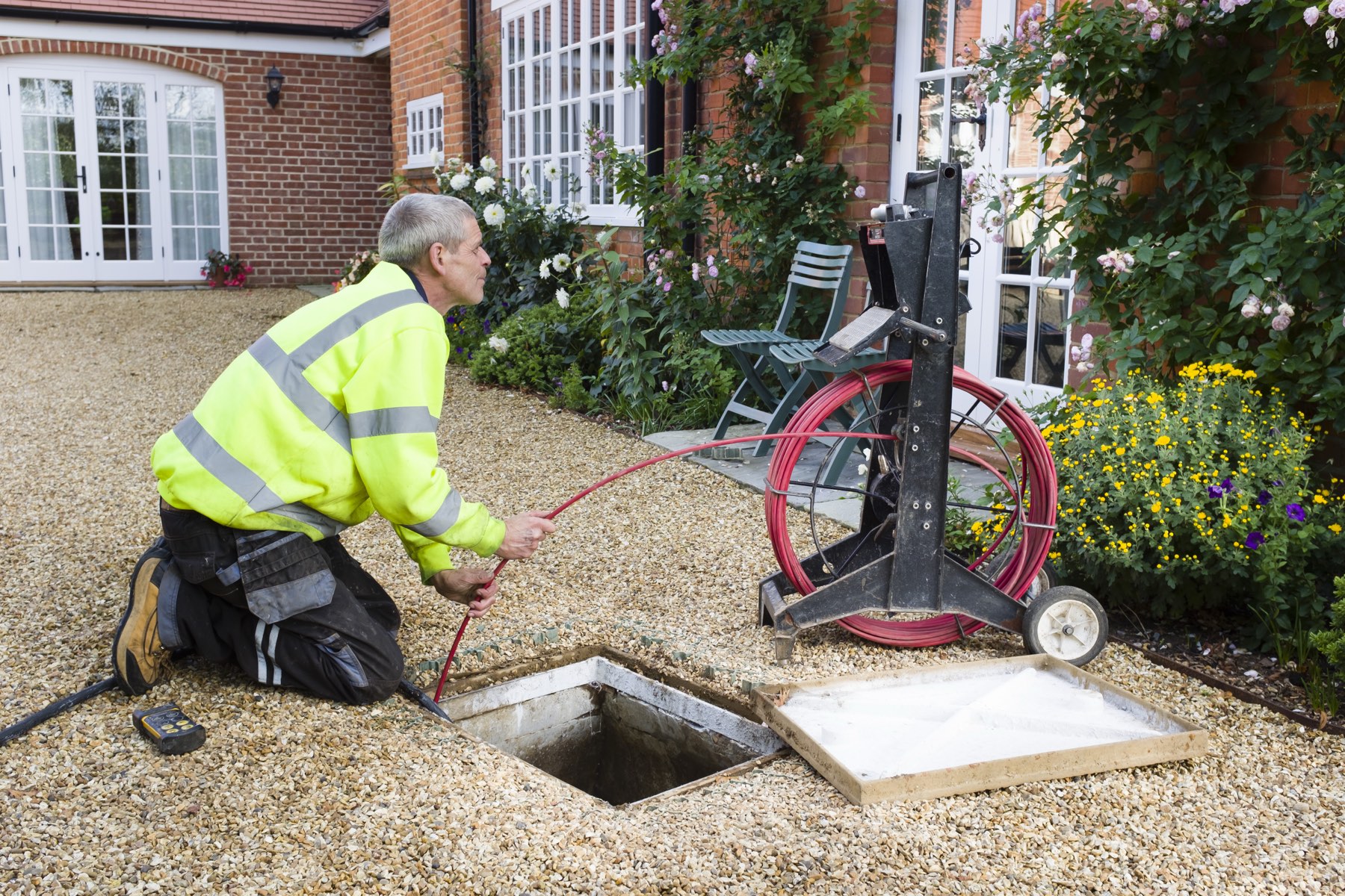 Drainage engineer clearing a drain at a house