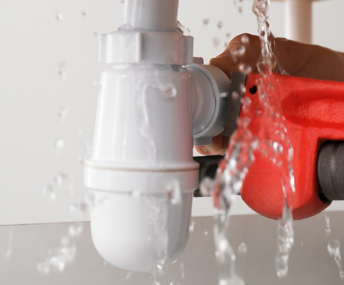 Plumber repairing a leaking waste pipe